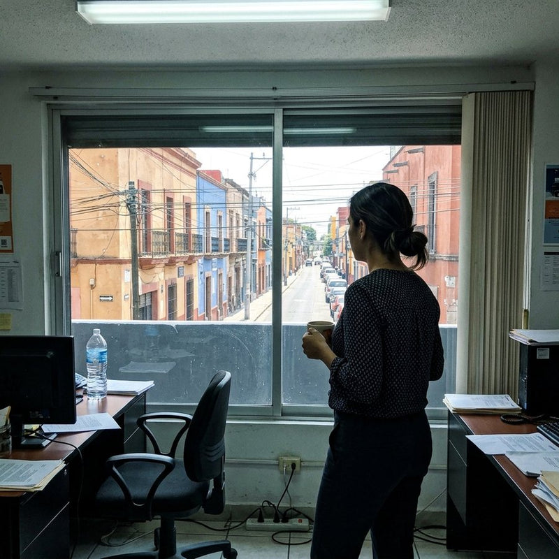 Mujer en la oficina mirando el sol por la ventana